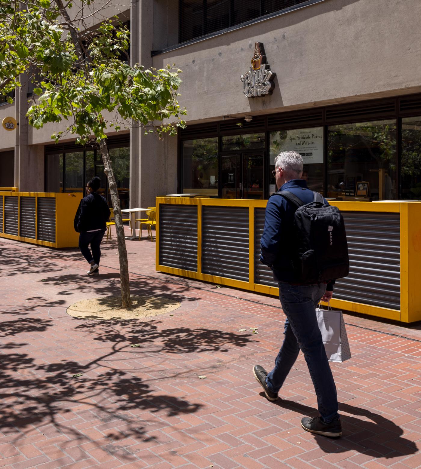 A man walking down the street outside Philz Coffee.